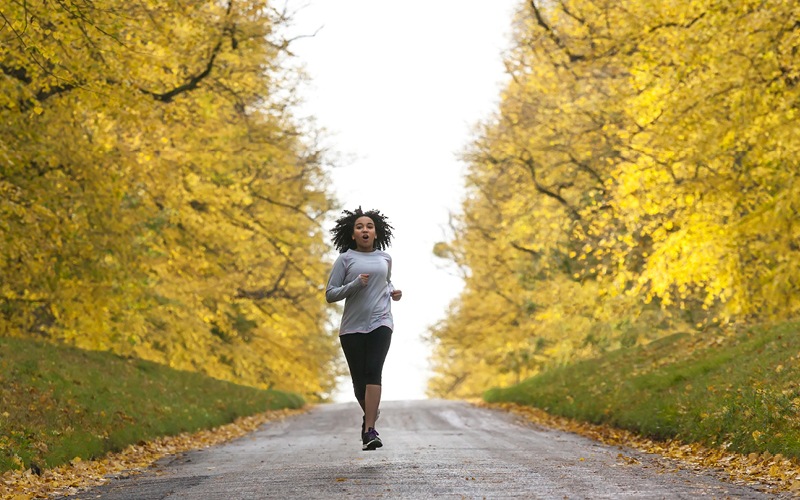 Woman running among golden trees